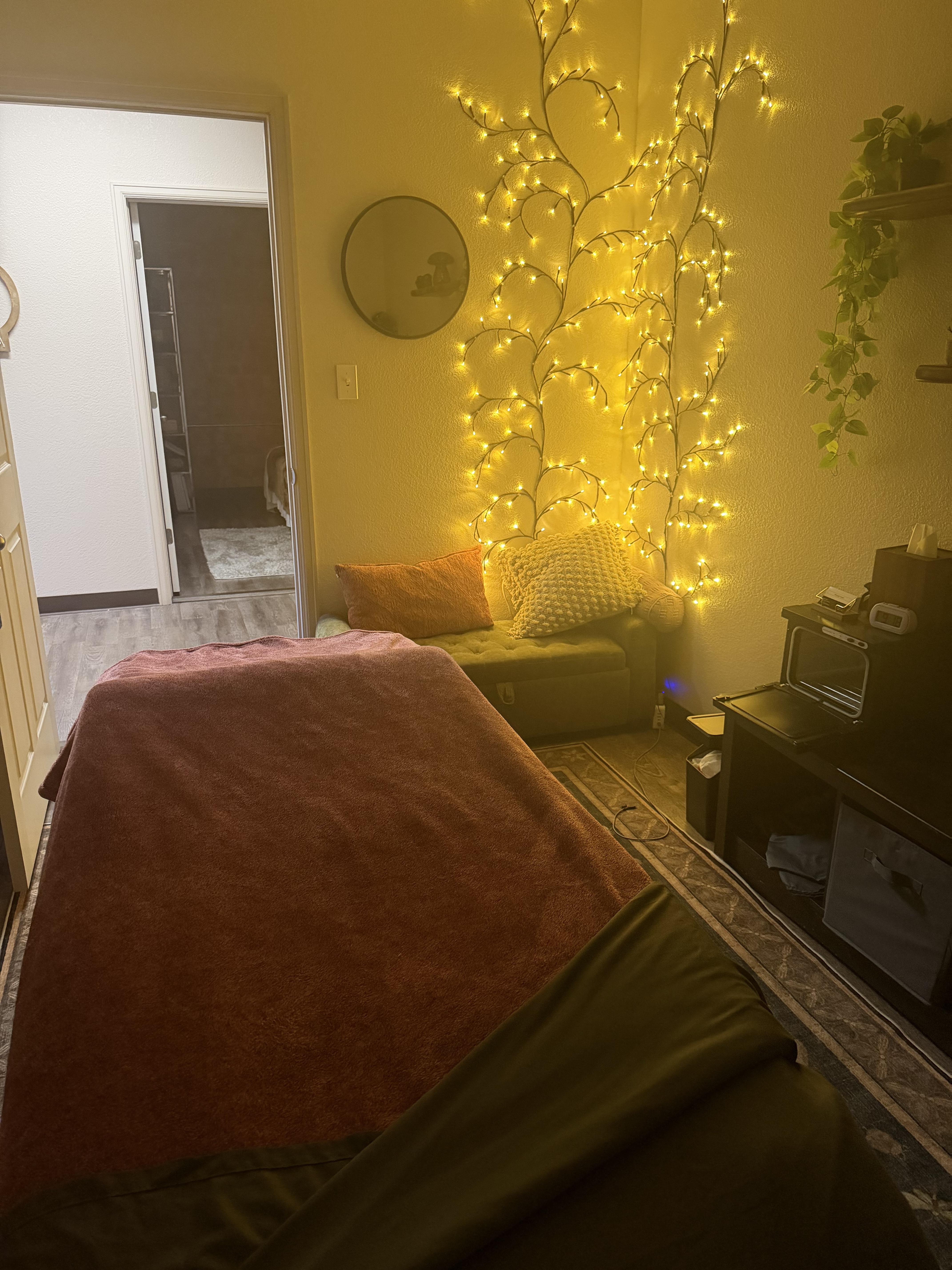 Rachel’s treatment room with warm string lights, a green chair, and its original open doorway