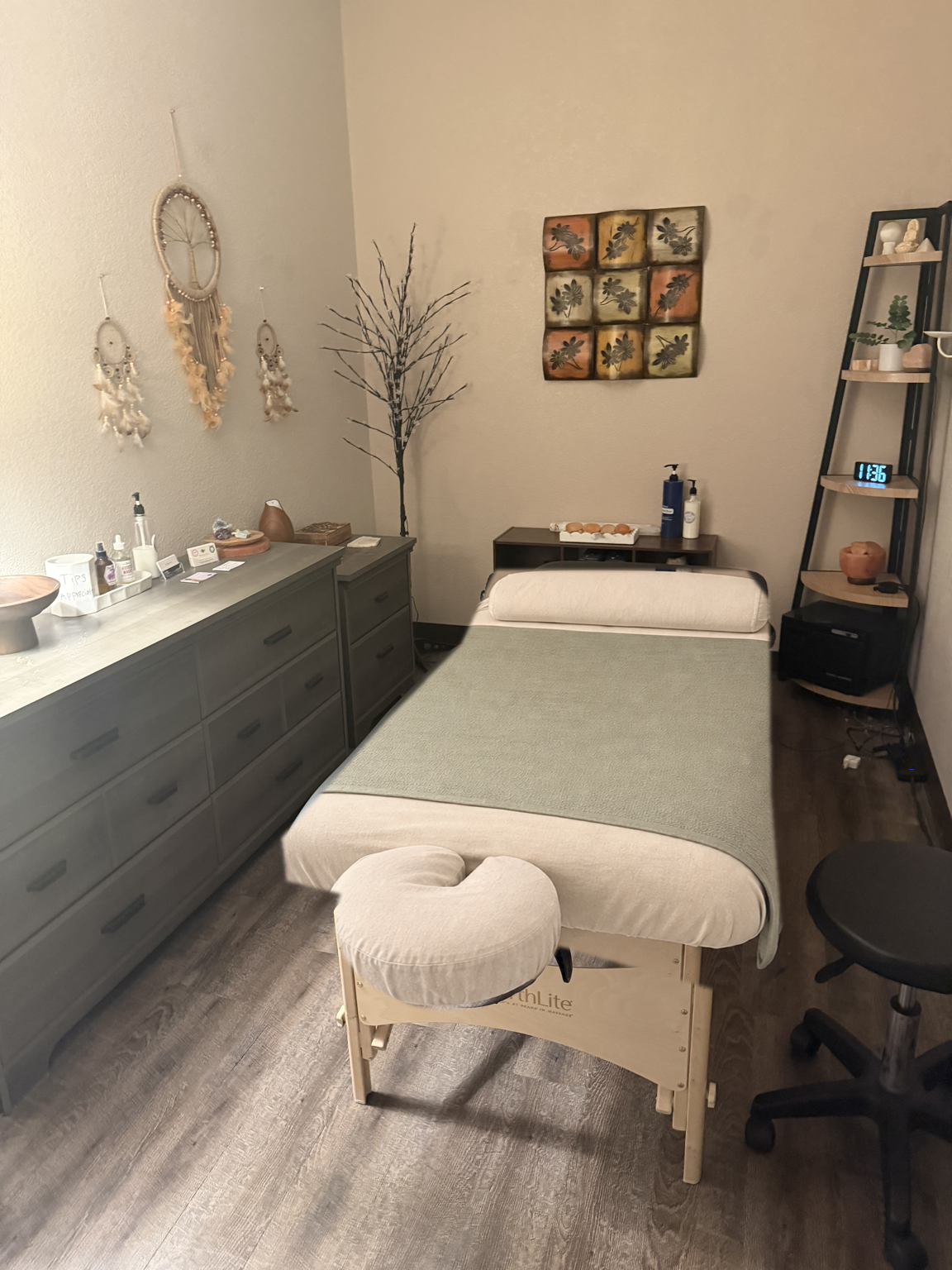 Danielle’s treatment room with original dreamcatchers, shelving, and a table dressed in ivory linens and a sage blanket